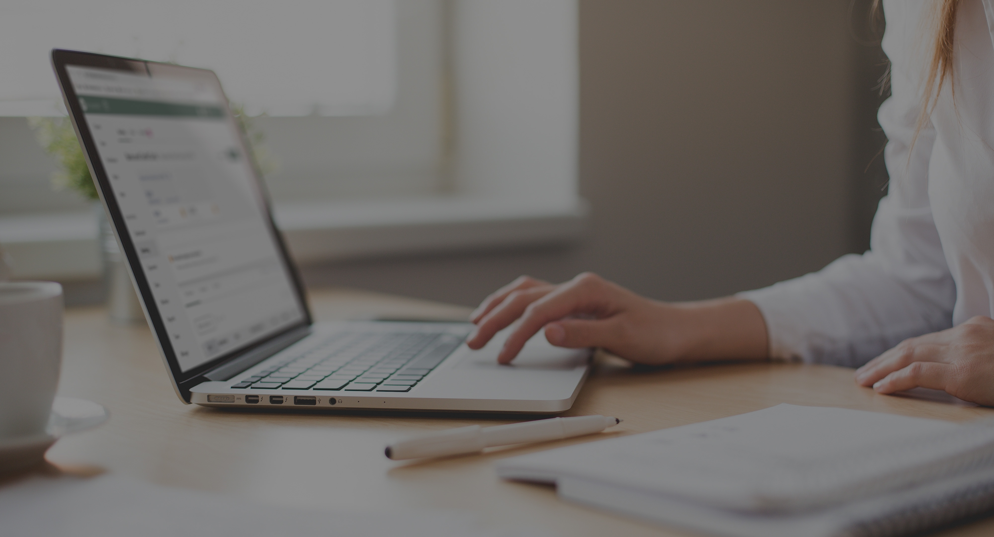 A woman seated at a desk works on a computer